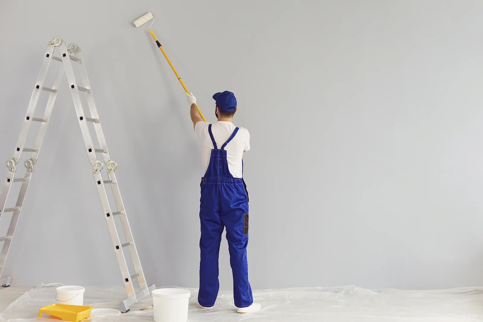 bigstock-Worker-Painter-Paints-A-Wall-b-371088577